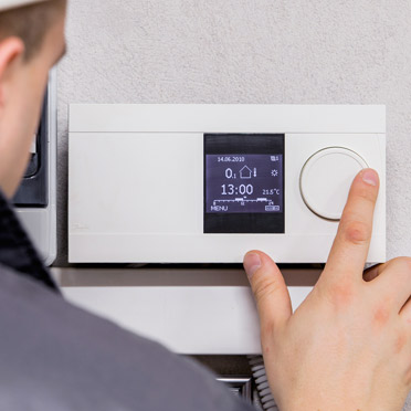 Expert configuring thermostat as part of HVAC services in Los Angeles.